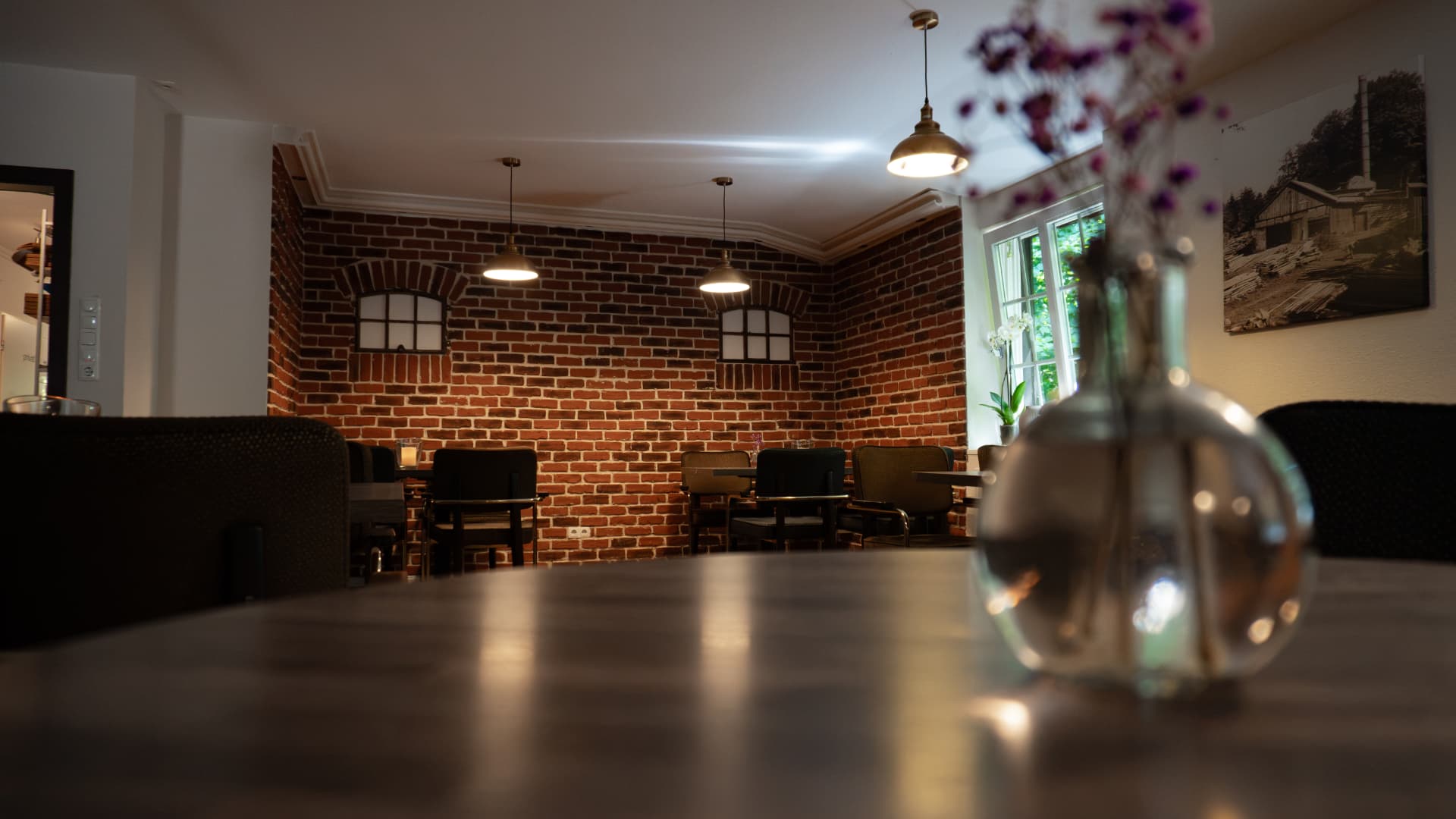 Gastraum mit Backsteinwand und Vase im Vordergrund